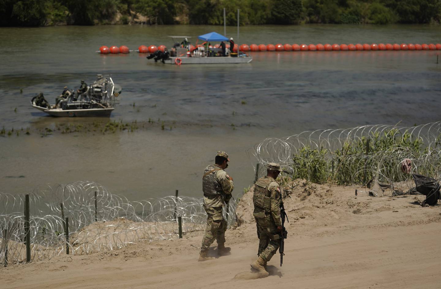 Vakter patruljerer langs grensen ved Rio Grande, der både  piggtråd og flytebøyer er satt opp for å avskrekke migranter fra å krysse elven.