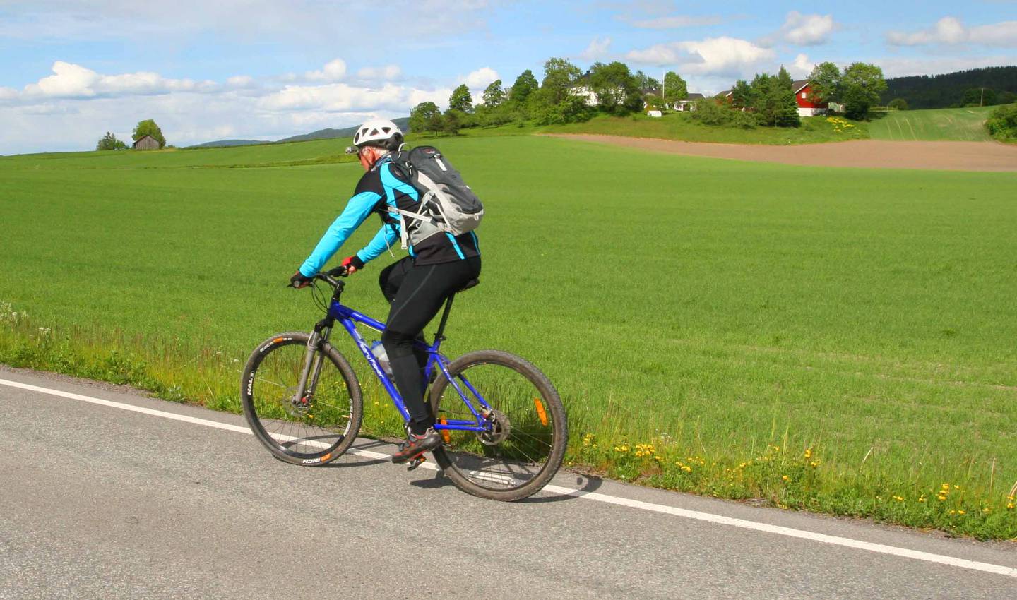 Sykkeltur i kulturlandskapet i Sande med Bø-gårdene i bakgrunnen.