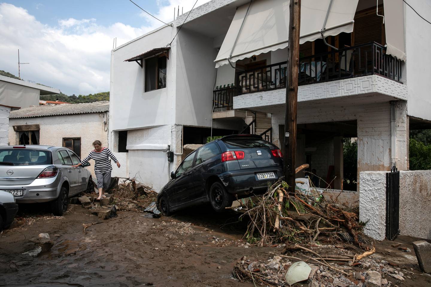 A woman walks between destroyed cars following a storm at the village of Politika, on Evia island, northeast of Athens, on Sunday, Aug. 9, 2020. Five people have been found dead and dozens have been trapped in their homes and cars from a storm that has hit the island of Evia, in central Greece, police say. (AP Photo/Yorgos Karahalis)