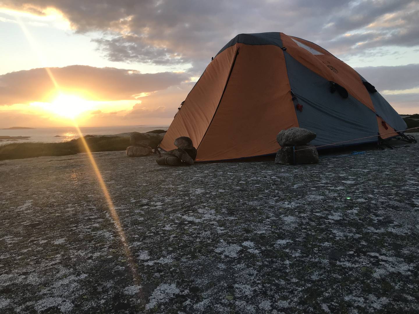 Et telt på et fjell i solnedgang