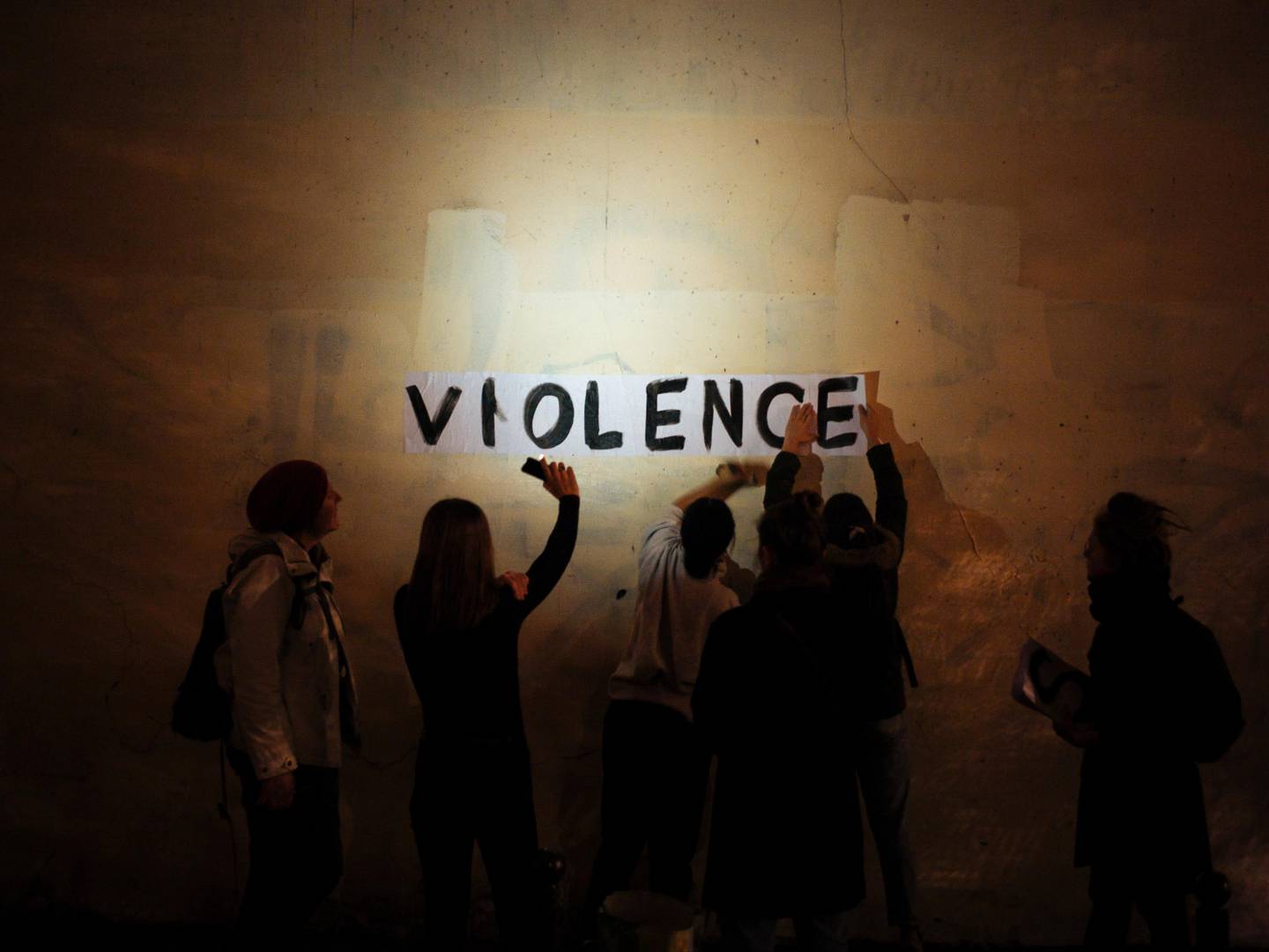 In this Oct. 31, 2019 photo, the word "violence" is pasted onto a wall by a group of women in a dark street in Paris. In Paris and cities across France, the signs are everywhere. "Complaints ignored, women killed" and "She leaves him, he kills her," they read in black block letters pasted over stately municipal buildings. Under cover of night, activists have glued them to the walls to draw attention to domestic violence, a problem French President Emmanuel Macron has called "France's shame." (AP Photo/Kamil Zihnioglu)