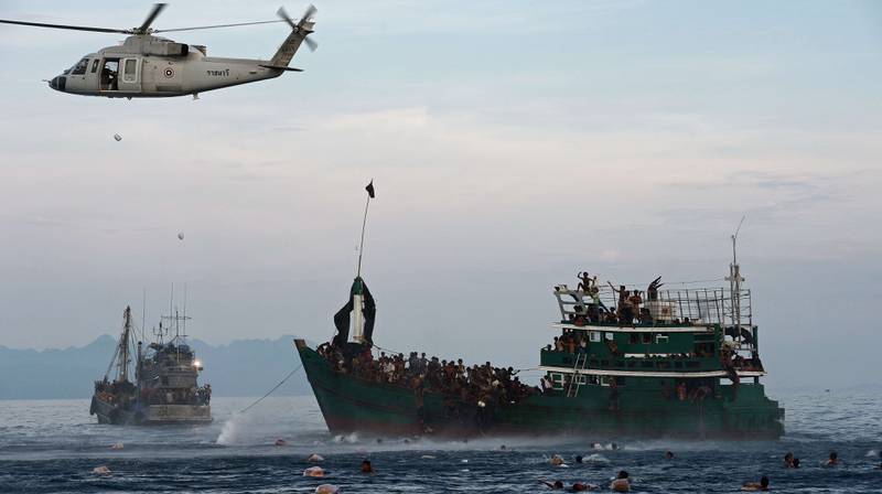 Båtflyktninger svømmer for å hente mat som ble sluppet ut av den thailandske hæren i dette bildet fra 14. mai. FOTO: NTB SCANPIX