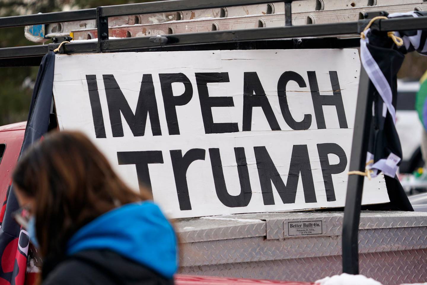 A sign stands in the bed of a pickup truck during a gathering calling for the impeachment of President Donald Trump at South High School before a car rally through the streets of downtown Sunday, Jan. 10, 2021, in Denver. More than 150 vehicles were guided by motorists calling for the removal from office of Trump as well as the resignations of Colorado Republican U.S. Representatives Lauren Boebert and Doug Lanborn for their support of Trump. (AP Photo/David Zalubowski)