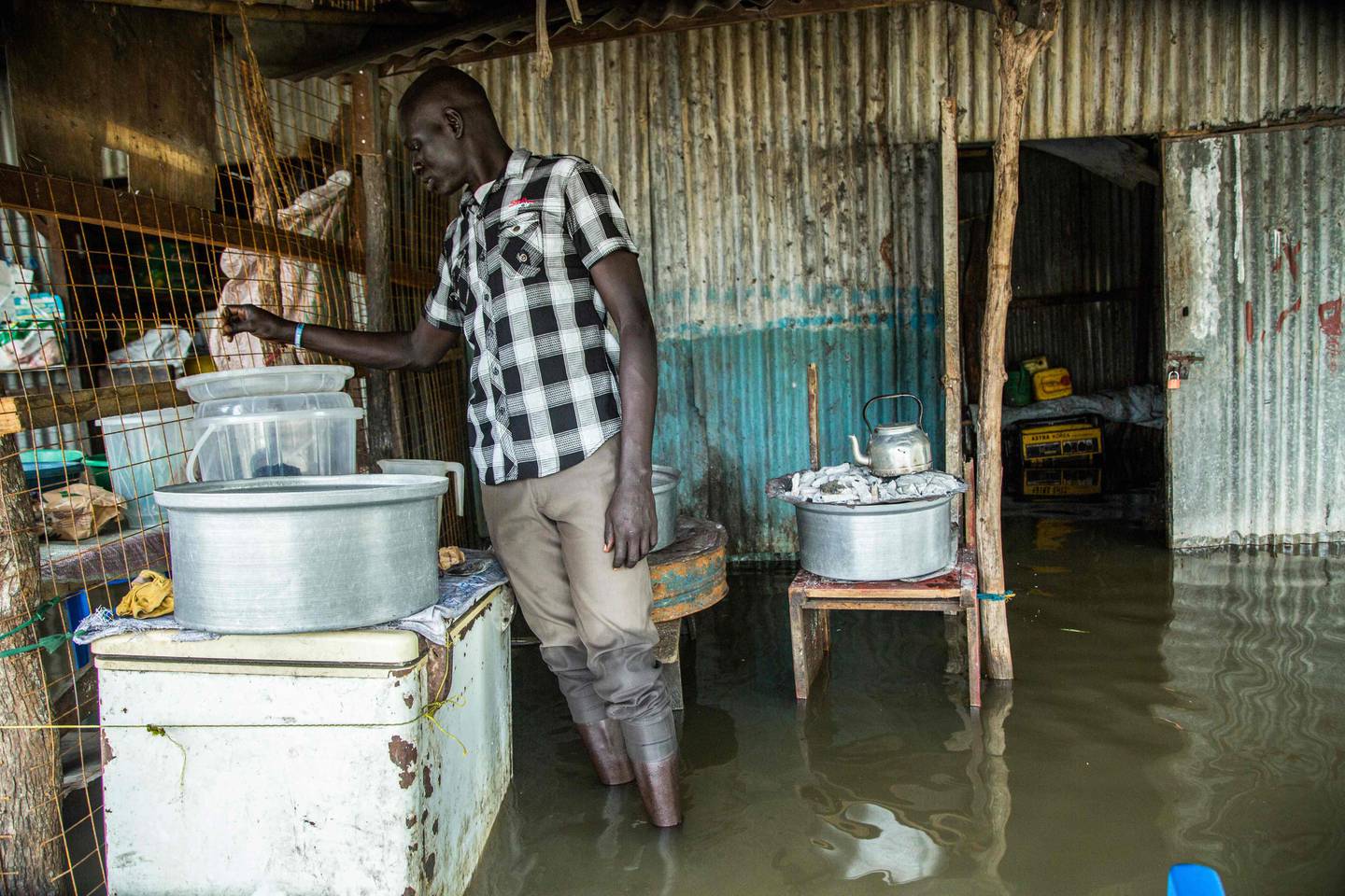 A man prepares tea in front of his shop in a flooded area after the Nile river overflowed after continuous heavy rain which caused thousands of people to be displaced in Bor, central South Sudan, on August 9, 2020. (Photo by Akuot CHOL / AFP)