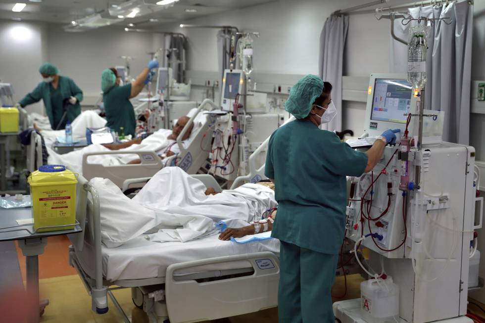 Tre sykepleiere i grønne klær på jobb på et sykehus i Beirut, pasienter ligger i sykesenger og det er slanger og skjermer og maskiner.