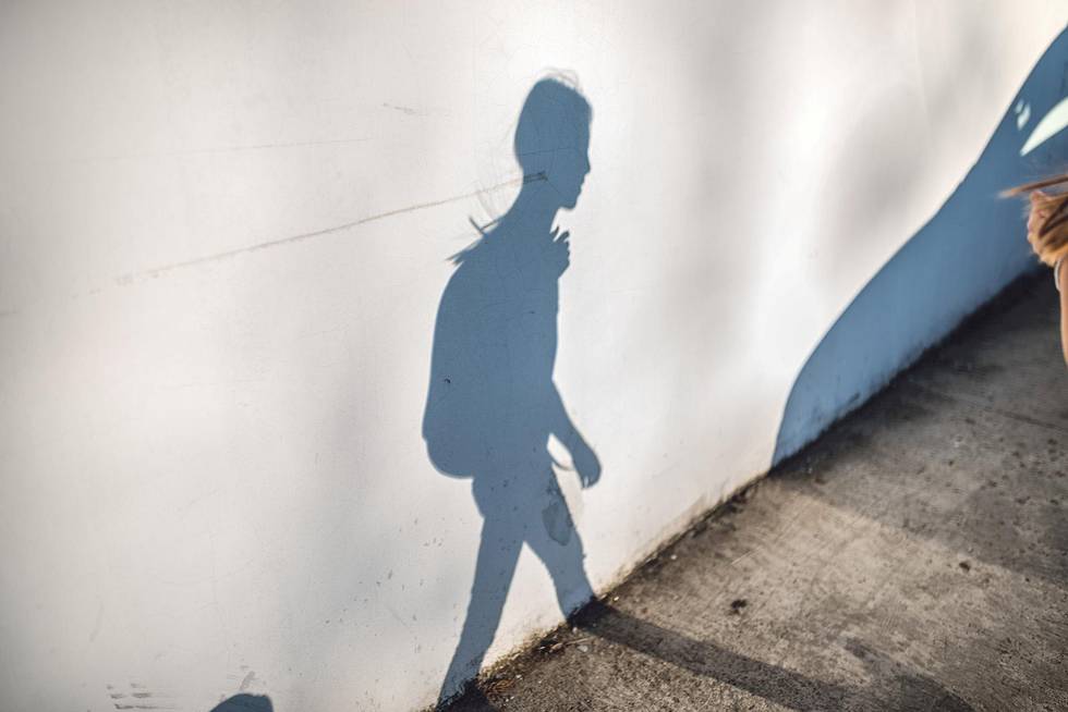 Shadow on the wall of girl wearing backpack walking to school