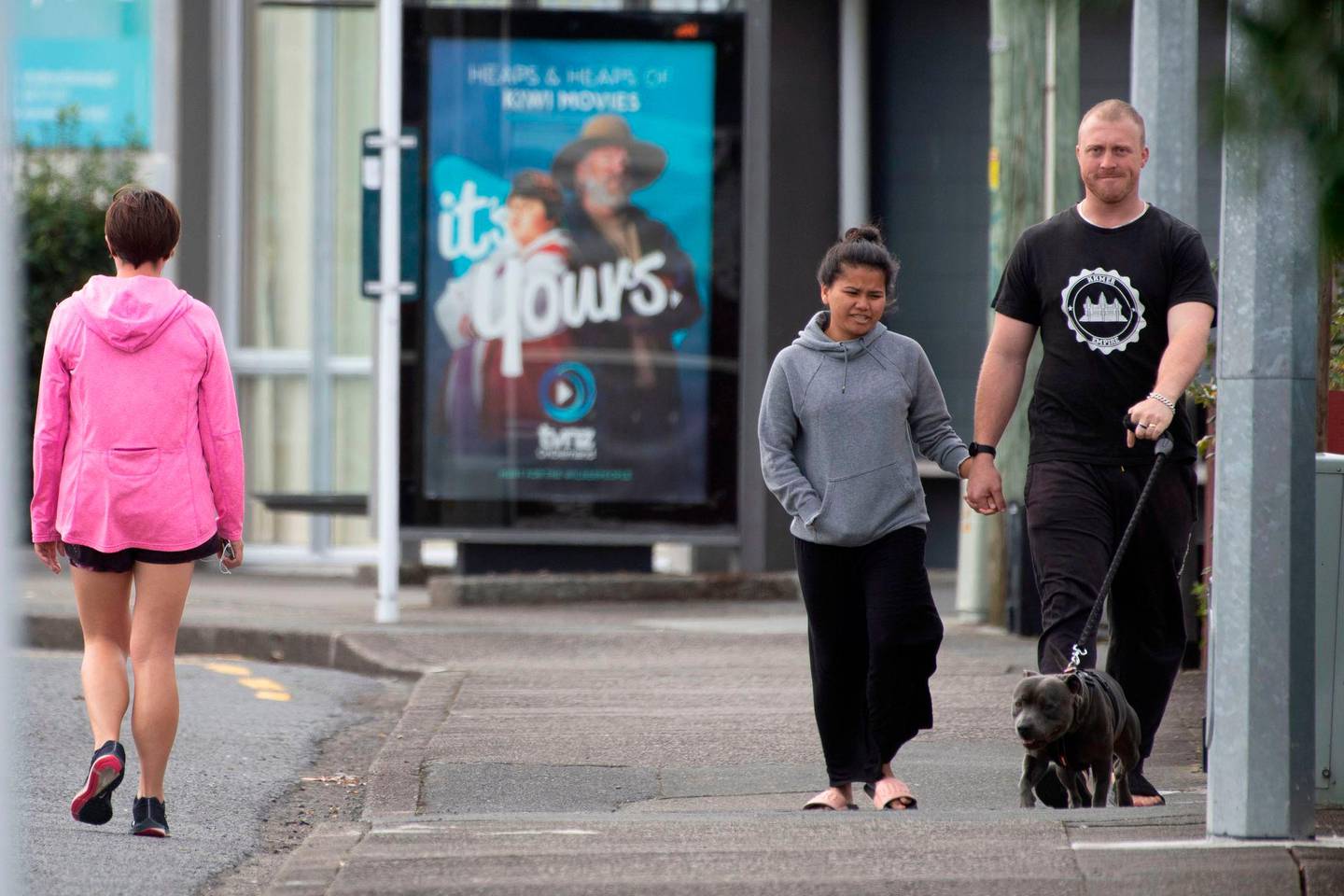 Pedestrians practise social distancing in response to the COVID-19 coronavirus outbreak along a street of Lower Hutt, near Wellington, on April 20, 2020. - New Zealand will ease a nationwide COVID-19 lockdown next week after claiming success in stopping "an uncontrolled explosion" of the virus, Prime Minister Jacinda Ardern said on April 20. (Photo by Marty MELVILLE / AFP)