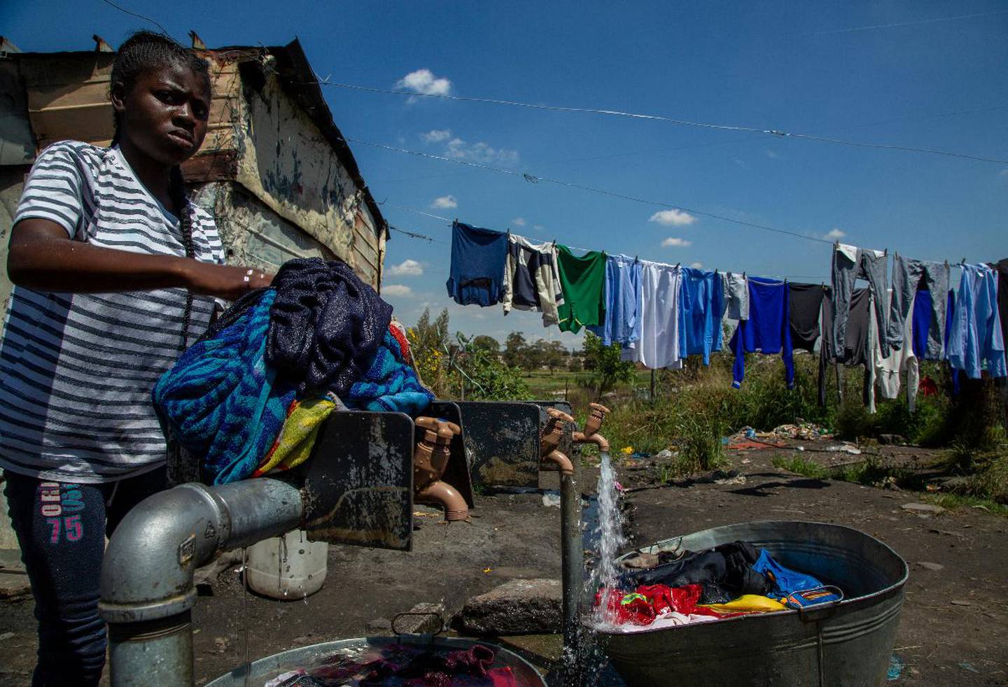 En kvinne vasker klærne under en kran i Soweto, Sør-Afrika. Koronaviruset truer nå de 1,3 milliarder menneskene som bor i Afrika.