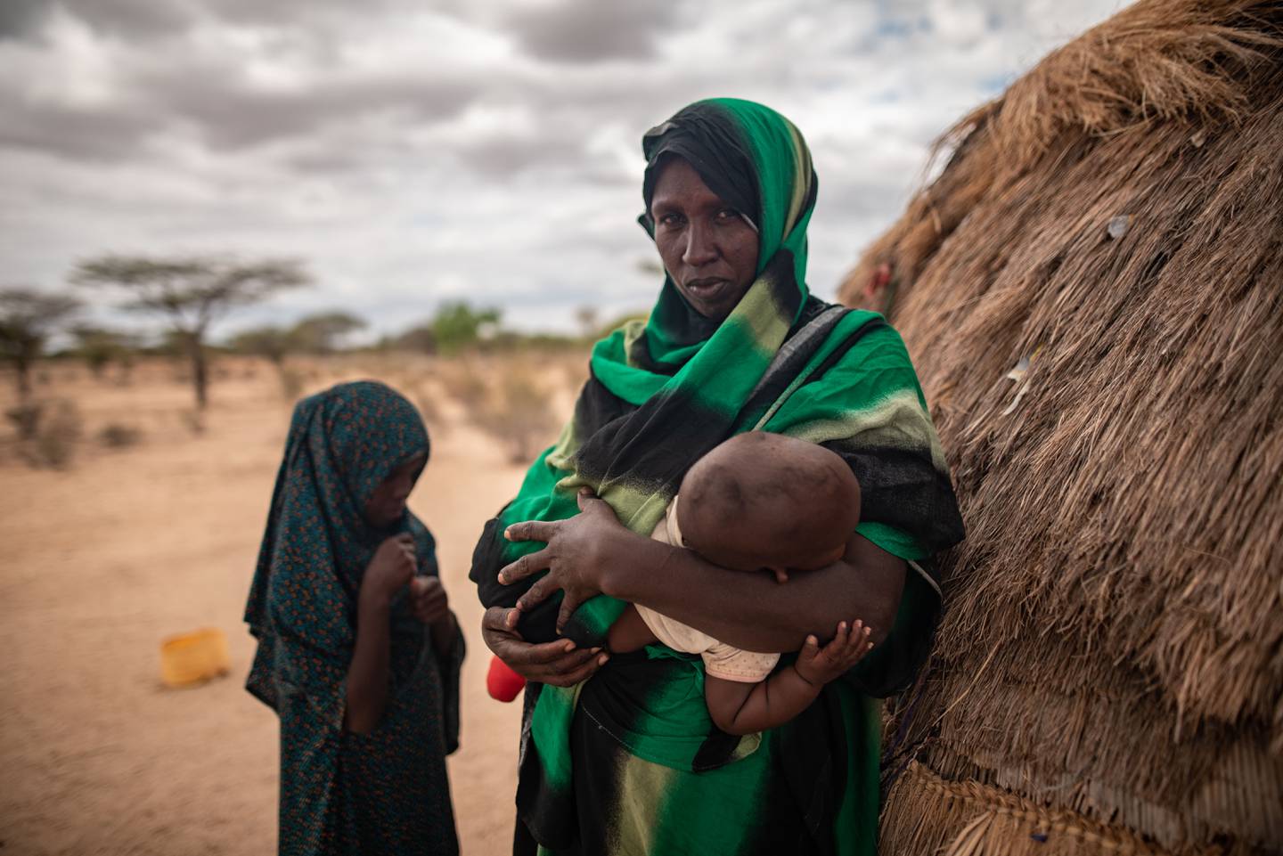 12 år gamle Mahad (t.v.) sammen med moren Batulo, med en åtte måneder gammel baby på armen, står utenfor familiens hjem i Garissa-provinsen i Kenya.