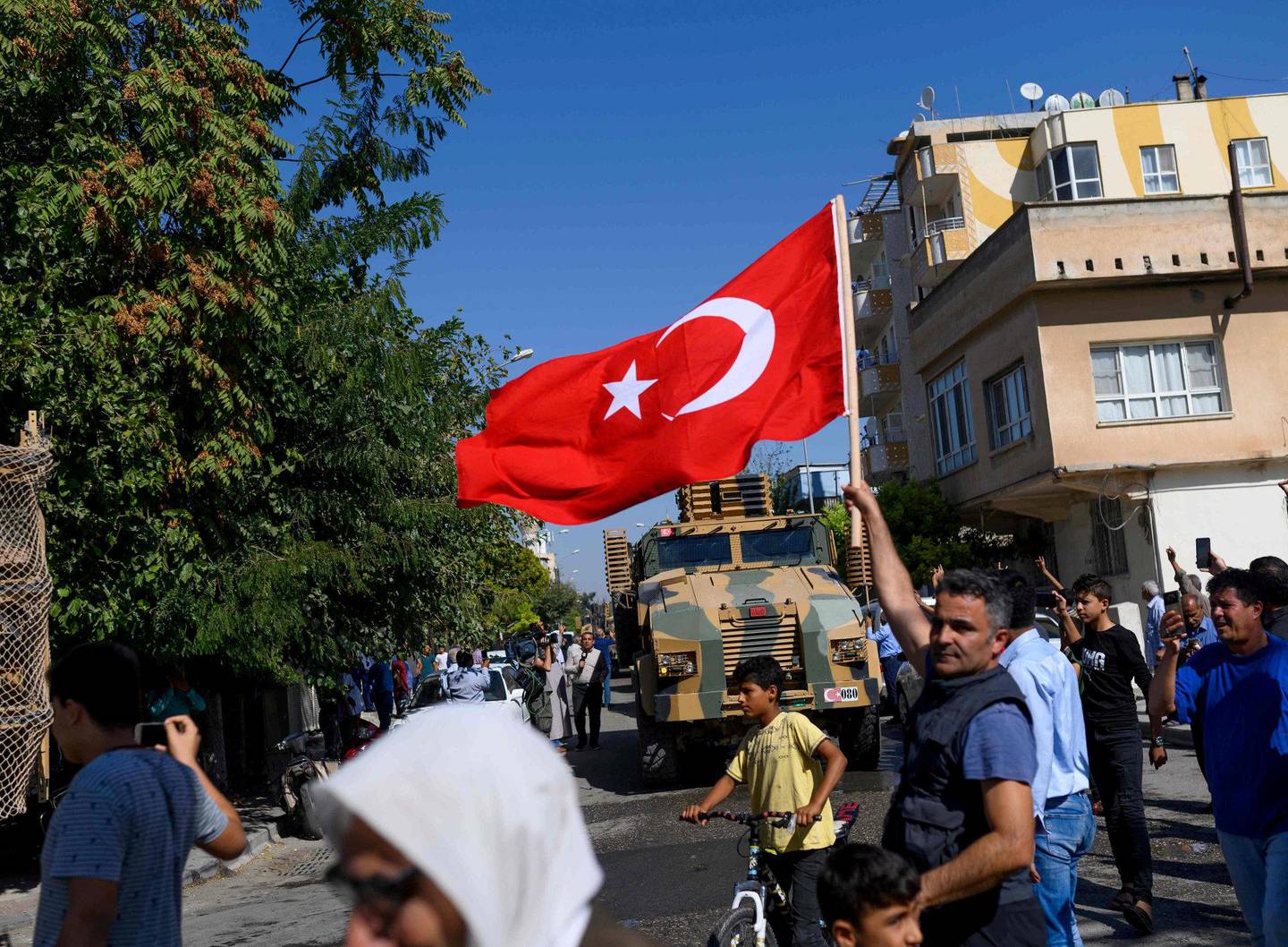 En mann vifter med et tyrkisk flagg foran tyrkiskstøttede syriske opposisjonssoldater i byen Akcakale i Tyrkia.FOTO: NTB SCANPIX
