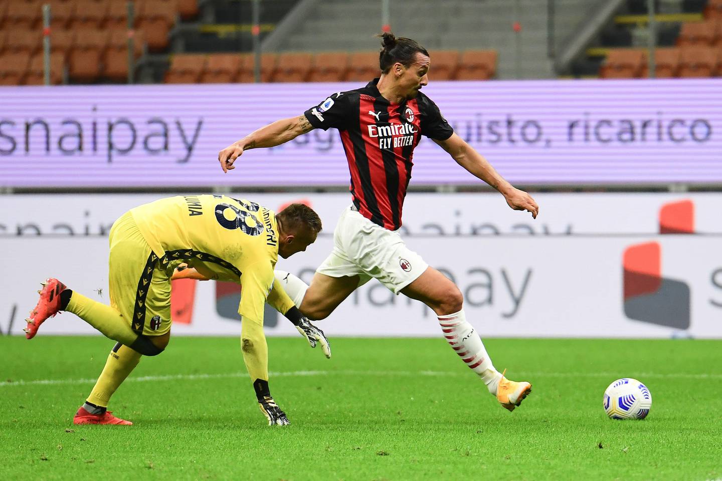 AC Milan's Swedish forward Zlatan Ibrahimovic (R) fights for the ball with Bologna's Polish goalkeeper Lukasz Skorupski during the Italian Serie A football match AC Milan vs Bologne at the San Siro stadium in Milan on September 21, 2020. (Photo by MIGUEL MEDINA / AFP)