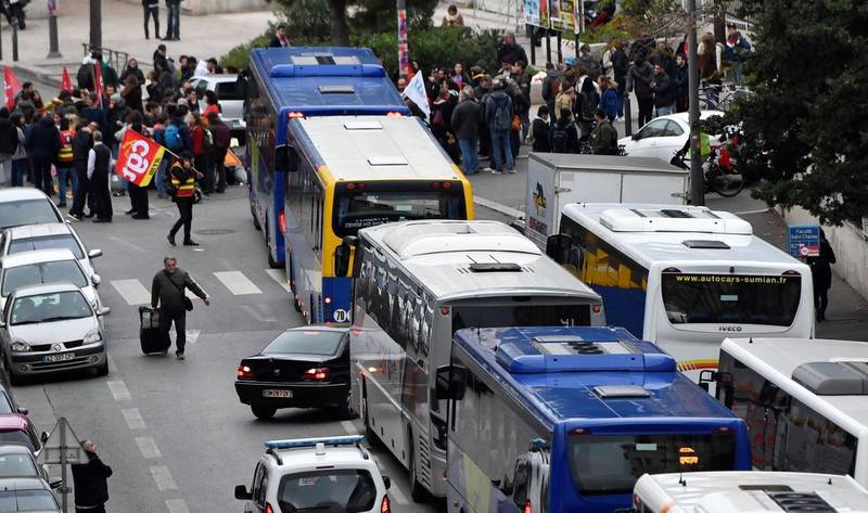 Members of the General Confederation of Labour (CGT), a French trade union and demonstrators block the buses leaving from the bus station by the Saint Charles university ahead of a march to protest against the pension overhauls, in Marseille, southern France, on December 5, 2019 as part of a national general strike. - Trains cancelled, schools closed: France scrambled to make contingency plans on for a huge strike against pension overhauls that poses one of the biggest challenges yet to French President's sweeping reform drive. (Photo by Clement MAHOUDEAU / AFP)