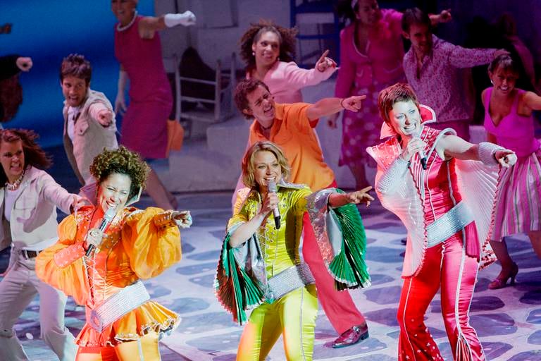 Scene med dansere og sangere kledd i sterke farger.