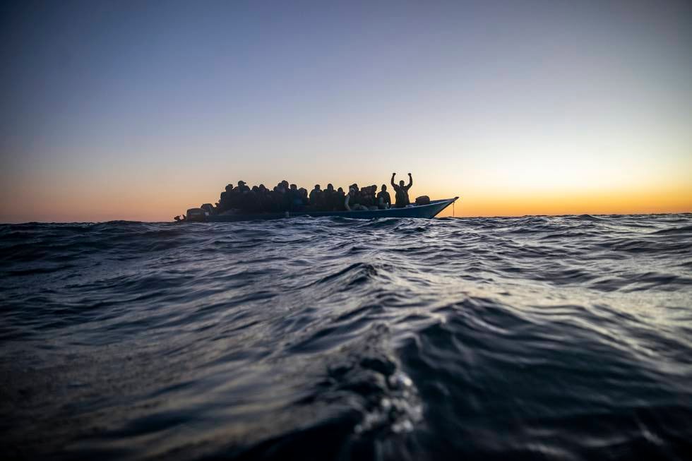 Migranter og flyktninger fra ulike afrikanske land sitter i en overfylt båt, og venter på hjelp av redningsmannskaper fra den spanske hjelpeorganisasjonen Open Arms. Bildet er tatt i februar 2021.