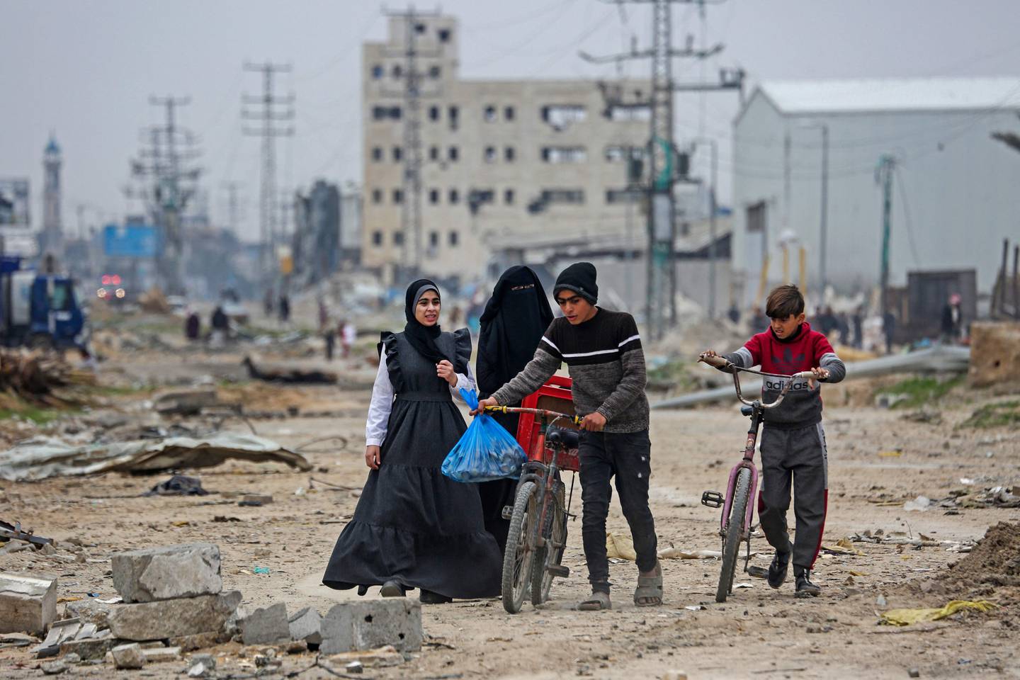 Palestinians walk amid debris in the Maghazi camp for Palestinian refugees, which was severely damaged by Israeli bombardment amid the ongoing conflict in Gaza between Israel and the Palestinian militant group Hamas, in the central Gaza Strip on February 27, 2024. (Photo by AFP)