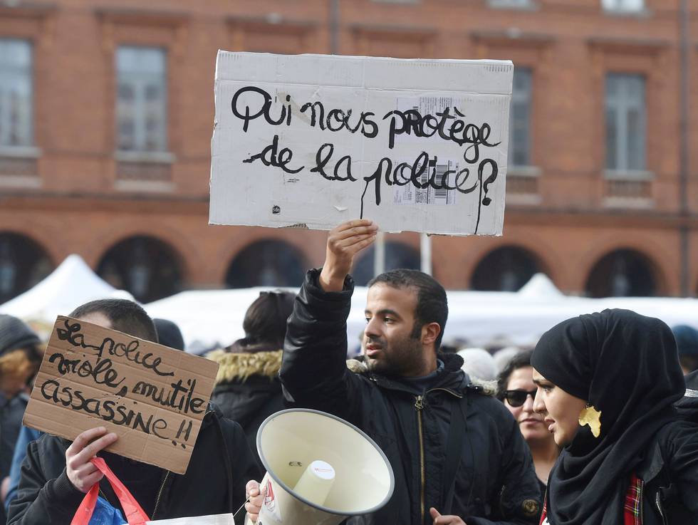 TOULOUSE: En mann holder opp en plaket der det står «Hvem beskytter oss fra politiet» under en demonstrasjon i Toulouse lørdag. FOTO: ERIC CABANIS/NTB SCANPIX
