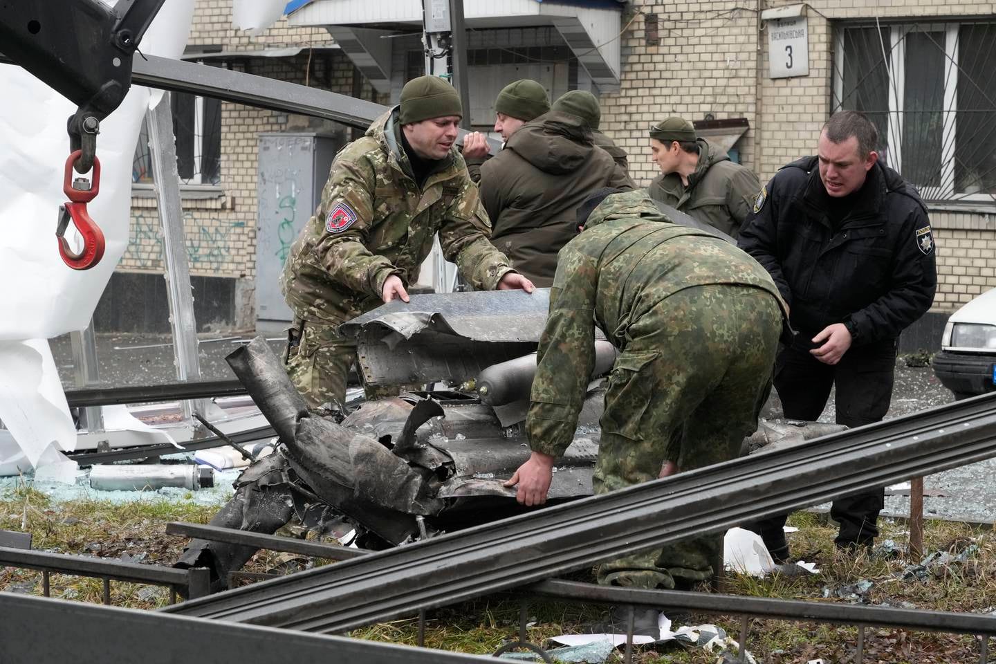 Ukrainske arbeidere jobber for å fjerne restene av en rakett etter russisk beskytning i Kyiv torsdag morgen.