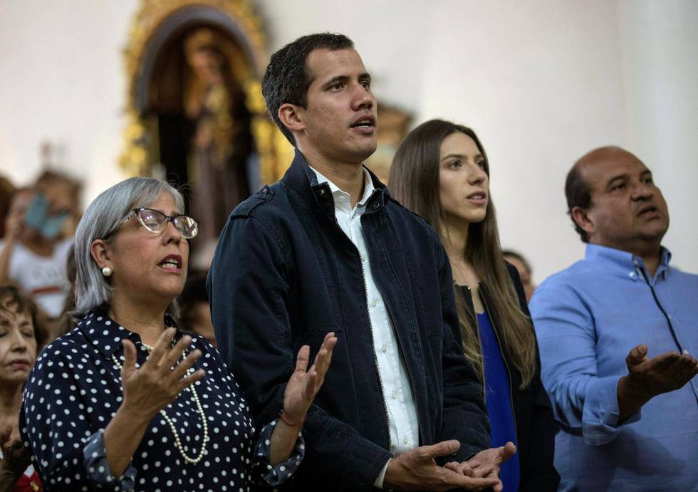 Opposisjonsleder Juan Guaidó ber sammen med kona Fabiana Rosales (til høyre) i en kirke i Caracas søndag. Guaidó hevder han vil lede landet ut av krisen og til et nyvalg. FOTO: RODRIGO ABD/NTB SCANPIX