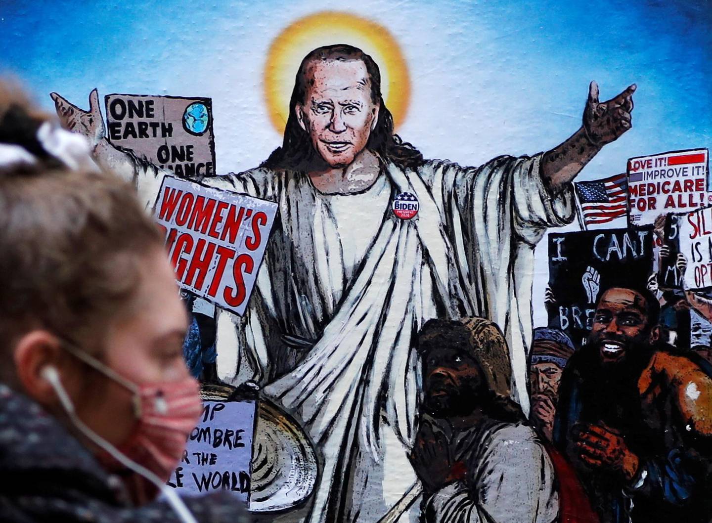A woman walks past a mural depicting U.S. President Joe Biden as Jesus addressing crowds of people titled 'The Saviour', created by artist Harry Greb in Rome, Italy, January 21, 2021. REUTERS/Yara Nardi     TPX IMAGES OF THE DAY