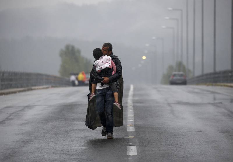Håp: En syrisk flyktning kysser datteren sin mens han går gjennom regnet til den greske grensen mot Makedonia i nord. FOTO: YANNIS BEHRAKIS/NTB SCANPIX