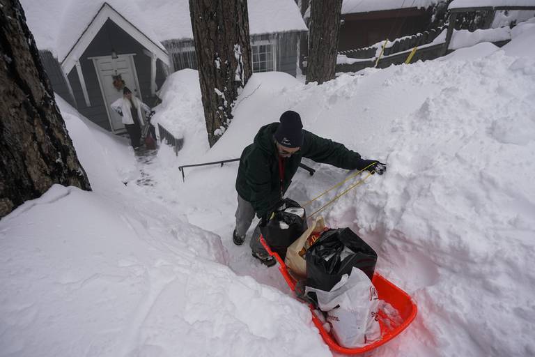 Angie Gourirand improviserer med et akebrett for å få hjem varene til huset sitt nedi snøen i Running Springs i California. Mer snø kan være på vei, så folk blir bedt om å holde seg hjemme.