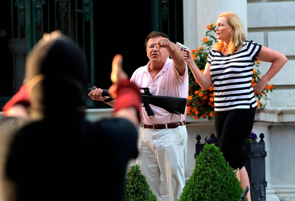 FILE - In this June 28, 2020 file photo, armed homeowners Mark and Patricia McCloskey, standing in front their house along Portland Place confront protesters marching to St. Louis Mayor Lyda Krewson's house in the Central West End of St. Louis. St. Louis top prosecutor told The Associated Press on Monday, July 20, 2020 that she is charging a white husband and wife with felony unlawful use of a weapon for displaying guns during a racial injustice protest outside their mansion. (Laurie Skrivan/St. Louis Post-Dispatch via AP File)