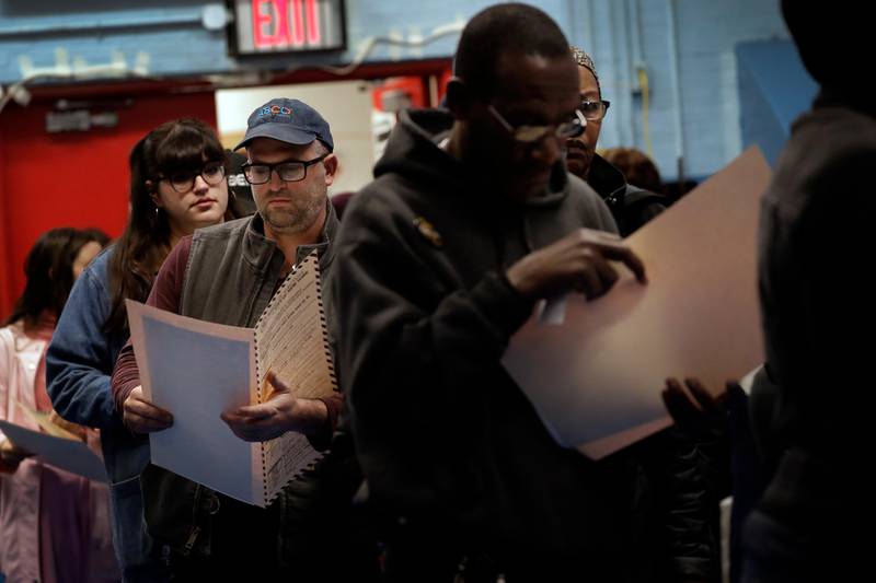 Voters read their ballot papers as they wait in line to cast their vote at P.S. 161 The Crown polling center on Tuesday, Nov. 6, 2018, in Brooklyn borough of New York. (AP Photo/Wong Maye-E)
