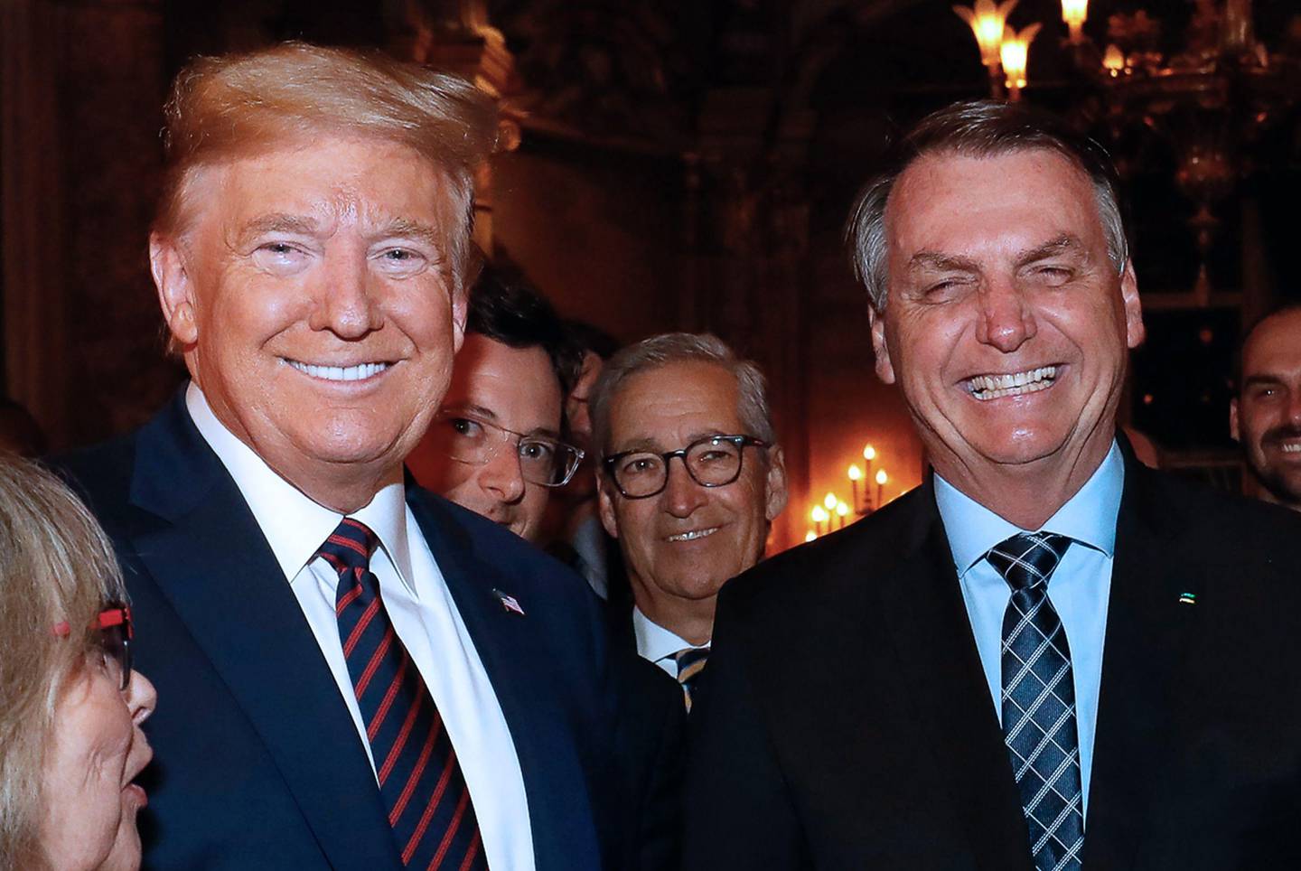 Handout picture released by the Brazilian Presidency on March 12, 2020 showing US President Donald Trump (L), Brazilian President Jair Bolsonaro (R) and his press advisor Fabio Wajngarten (2-L, behind Trump) during a dinner in Mar a Lago, Florida, United States, on March 7, 2020. - Brazilian President Jair Bolsonaro's communications chief, Fabio Wajngarten, who met US President Donald Trump last weekend at his Florida resort, has tested positive for the new coronavirus, the government said on March 12, 2020. Wajngarten, chief spokesman for the Brazilian government, travelled with Bolsonaro last Saturday to Tuesday to the United States. (Photo by Alan SANTOS / BRAZILIAN PRESIDENCY / AFP) / RESTRICTED TO EDITORIAL USE - MANDATORY CREDIT "AFP PHOTO / BRAZIL'S PRESIDENCY / ALAN SANTOS" - NO MARKETING - NO ADVERTISING CAMPAIGNS - DISTRIBUTED AS A SERVICE TO CLIENTS