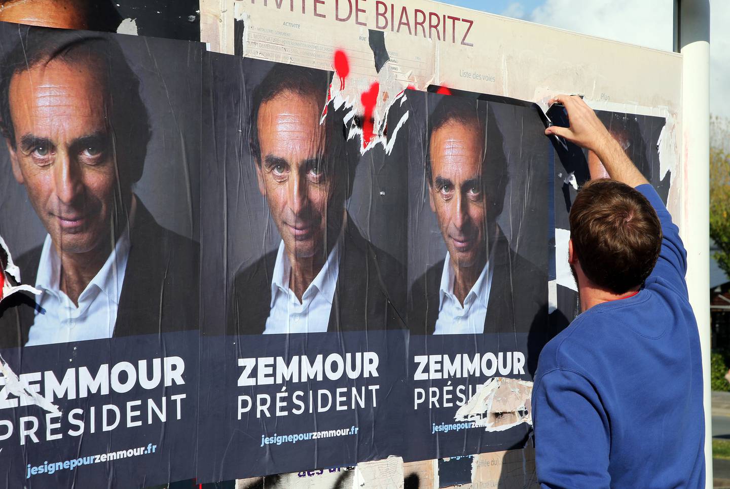 En mann river ned en plakat med bilde av Zemmour. 63-åringen har ennå ikke sagt om han stiller i neste års presidentvalg, men det er likevel hengt opp flere plakater med påskriften "Zemmour president".