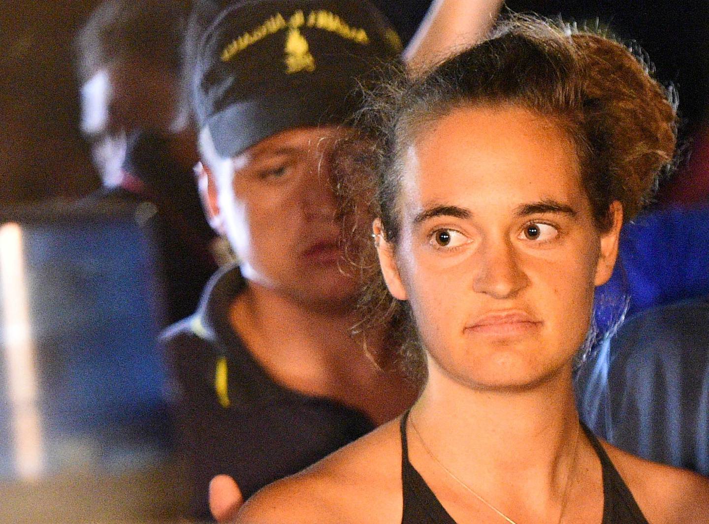 FILE PHOTO: Carola Rackete, 31-year-old Sea-Watch 3 captain, is escorted off the ship by police and taken away for questioning, in Lampedusa, Italy, June 29, 2019. REUTERS/Guglielmo Mangiapane/File Photo