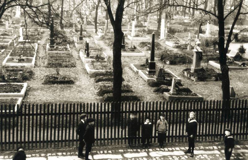 Kirkegården på Sofienberg var forbudt område for barna på Grünerløkka, og kirkegårdsvakta jaget barna ut. I midten på bildet, med hvit krave, står Nils E. Nilsson. Faren hans har stått i leiligheten i Sofienberggata 29 og fotograferte guttegjengen foran den vestre delen av kirkegården omkring 1920. 