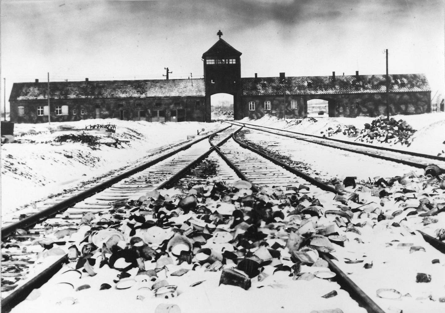 Inngangen til Auschwitz fotografert i mars/april 1945. I forgrunnen, på skinnene, sees personlige gjenstander forlatt av de utallige menneskene som ankom utryddelsesleiren. Foto: AP/NTB scanpix