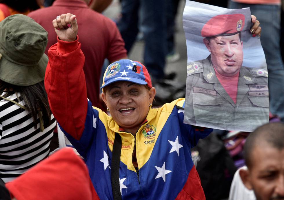 Nåværende president Nicolás Maduro vant valget i kjølvannet av president Hugo Chávez’ død i 2013, som hans foretrukne etterfølger. Da hadde Chávez ledet den såkalte «bolivarianske revolusjonen» i 14 år. Her en tilhenger av Maduro med plakat med bilde av avdøde Chavez under en demonstrasjon til  støtte for regjeringen.
