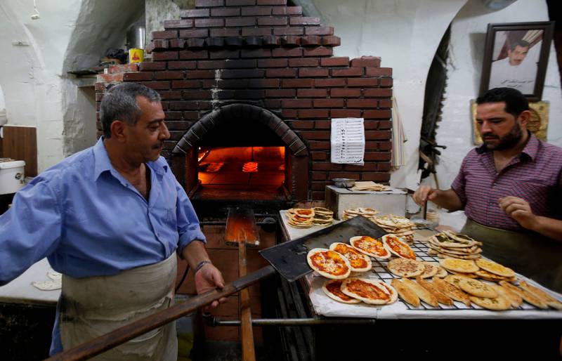 Syrian men work in their bakery in old Damascus, on June 16, 2020. - The Caesar Syria Civilian Protection Act of 2019, a US law that aims to sanction any person who assists the Syrian government or contributes to the country's reconstruction, is to come into force on June 17. (Photo by LOUAI BESHARA / AFP)