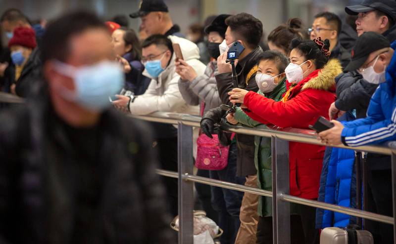 People wear face masks as they wait for arriving passengers at Beijing Capital International Airport in Beijing, Thursday, Jan. 23, 2020. China closed off a city of more than 11 million people Thursday, halting transportation and warning against public gatherings, to try to stop the spread of a deadly new virus that has sickened hundreds and spread to other cities and countries in the Lunar New Year travel rush. (AP Photo/Mark Schiefelbein)