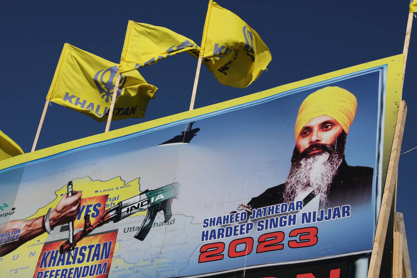 Et banner viser den drepte sikh-aktivisten Hardeep Singh Nijjar ved siden av flagg for et uavhengig Khalistan.