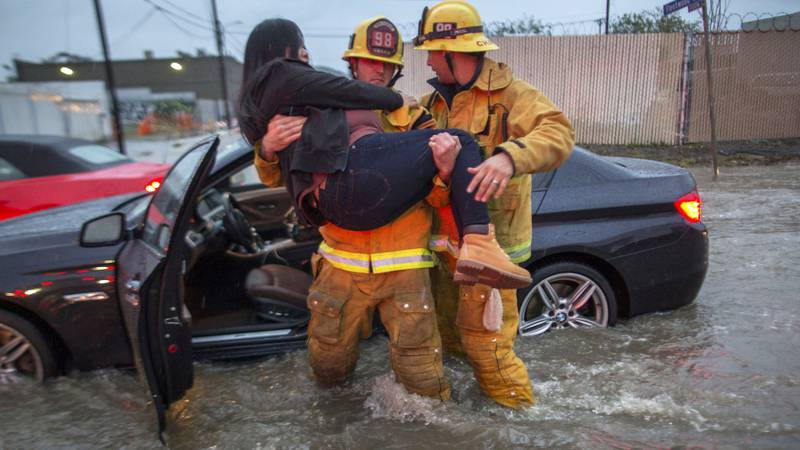 En brannmann bærer en kvinne fra bilen hennes etter at den ble fanget i en oversvømmelse etter at en storm beveget seg over den sørlige delen av California i februar i år. Hundrevis av innbyggere måtte evakueres etter at det begynte å regne tungt etter flere år med alvorlig tørke. 