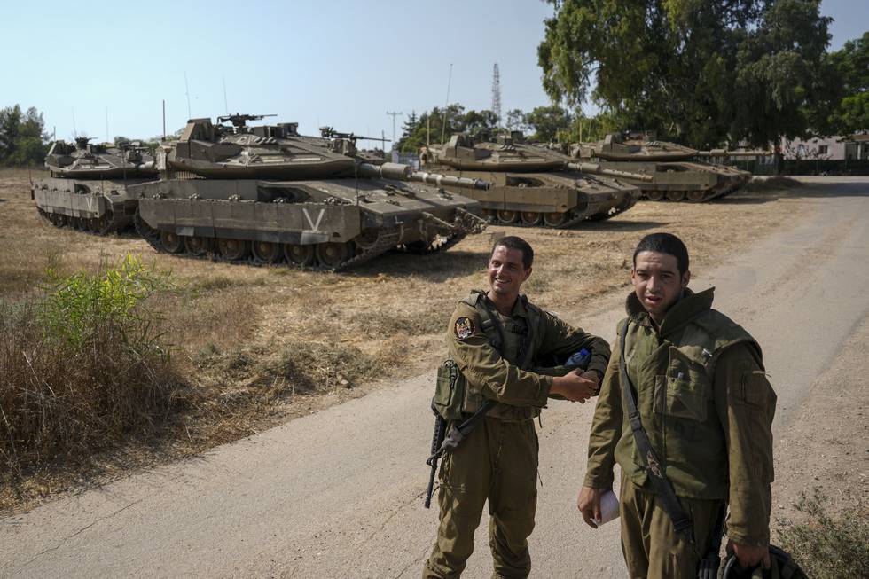 Israelske soldater fotografert ved sine stridsvogner i et område i nærheten av Gazastripen fredag. Israel stengte tidligere denne uka veier nær den palestinske enklaven og sendte forsterkninger dit i påvente av et mulig gjengjeldelsesangrep. Foto: Ariel Schalit / AP / NTB