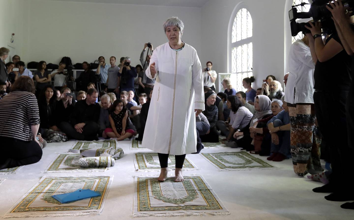 Seyran Ates, stående i midten, grunnlegger av Ibn-Rushd-Goethe-moskeen, gestikulerer under åpningen av moskeen i Berlin, Tyskland, fredag 16. juni 2017. Ates, 54 år gammel datter av tyrkiske innvandrere, har grunnlagt den første liberale moskeen i Tyskland der menn og kvinner kan be sammen, homofile er velkomne og muslimer fra alle sekter kan legge sine indre religiøse konflikter bak seg.