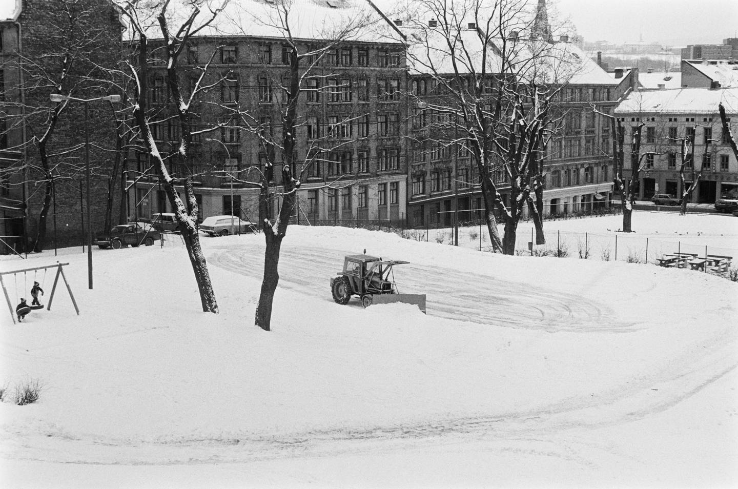 Snørydding mens barn leker i Kristparken, tidligere Krist kirkegård, ca. 1982-1983. Til venstre Deichmans gate og til høyre Møllergata.