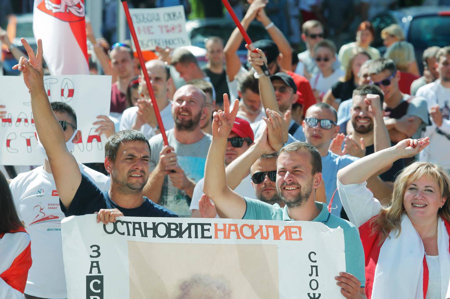 People hold a banner reading "Stop violence!" during a rally near the Belarus Television headquarters in Minsk, Belarus, Monday, Aug. 17, 2020.  Thousands of factory workers are taking to the streets of Minsk demanding the resignation of authoritarian President Alexander Lukashenko, in the ninth straight day of protests against an election that extended his long rule over the country. (AP Photo/Dmitri Lovetsky)
