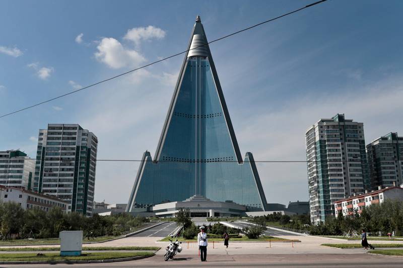 A traffic policeman is dwarfed by the 105-story Ryugyong Hotel in Pyongyang, North Korea, Wednesday, Sept. 11, 2019. Construction of the pyramid-shaped hotel, the capital city's most conspicuous landmark, began in 1987 but the work has not been completed and it has never hosted any guests. It is believed to be the tallest unfinished building in the world. (AP Photo/Dita Alangkara)