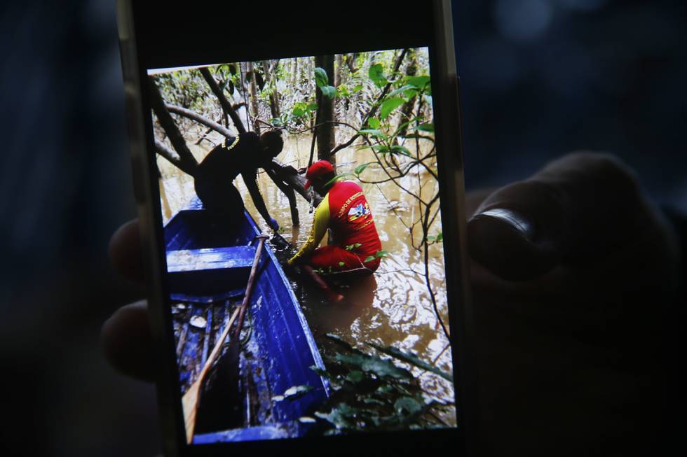 Ryggsekken var knyttet til et tre som var delvis nedsunket, forteller en brannmann og viser fram et mobilbilde av funnstedet. Foto: Edmar Barros / AP / NTB