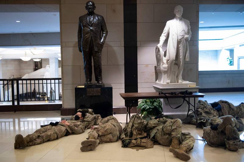 Members of the National Guard rest on Capitol Hill on January 14, 2021, in Washington, DC, a week after supporters of US President Donald Trump attacked the US Capitol, and ahead of the inauguration of President-elect Joe Biden on January 20. (Photo by Brendan Smialowski / AFP)