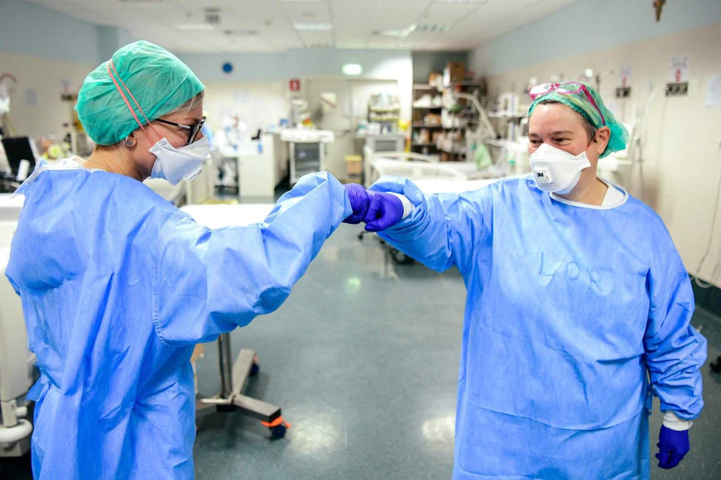 TOPSHOT - Members of the medical staff give themselves a fist bump while working at the intensive care unit (ICU) with the COVID-19 patients at the ASST Papa Giovanni XXIII hospital in Bergamo, on April 3, 2020. - Italy's three-week lockdown to stop the spread of COVID-19 has been extended through at least mid-April and its economy is expected to suffer its biggest peacetime shock since World War II. (Photo by Piero CRUCIATTI / AFP)