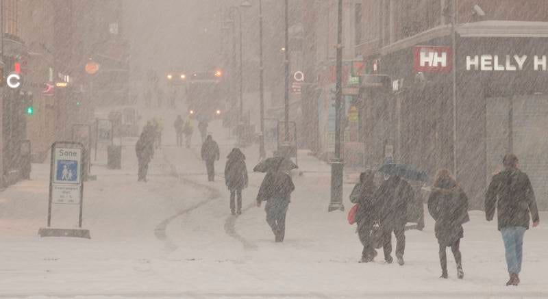 Folk på vandring i snøføyka på Karl Johans gate torsdag morgen. FOTO: PAUL KLEIVEN/NTB SCANPIX