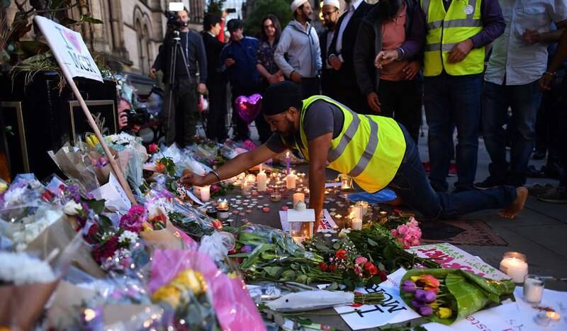 En mann legger ned en rose på et minnested i Albert Square i Manchester etter terroraksjonen mot Manchester Arena hvor minst 22 mennesker ble drept natt til tirsdag.