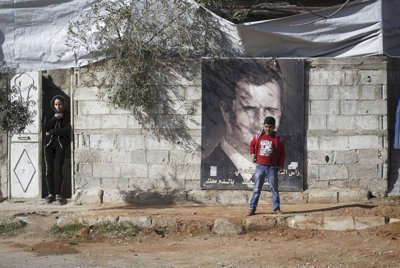 En plakat av president Bashar al-Assad henger på en vegg i campen Wafideen utenfor Damaskus. Campen er kontrollert av syriske styrker, som nå også nærmer seg IS-hovedstaden Raqqa nord i landet. FOTO: Omar Sanadiki/NTB SCANPIX
