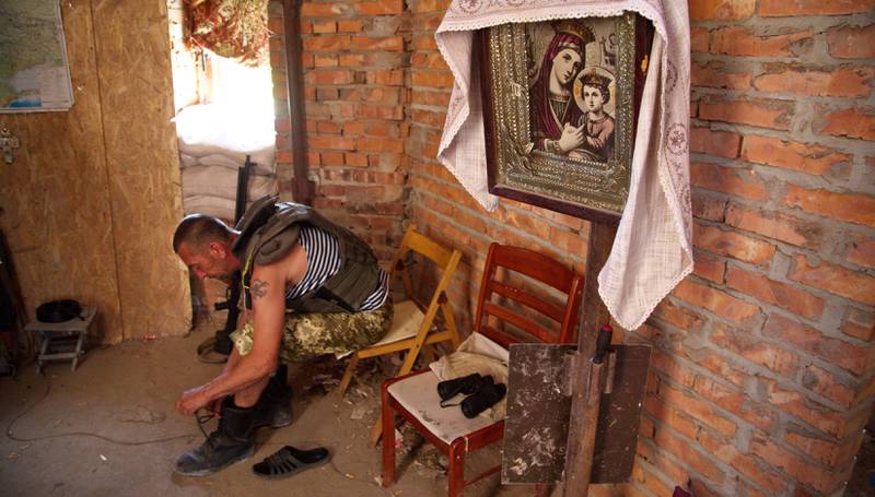 En ukrainsk soldat knyter opp støvlene i en bombet ortodoks kirke i landsbyen Pisky øst i Ukraina. FOTO: NTB SCANPIX