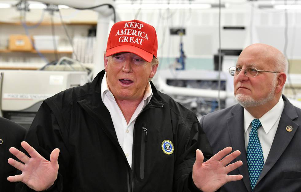 President Donald Trump speaks to members of the press as Director Robert Redfield, right, looks at the headquarters of the Centers for Disease Control and Prevention in Atlanta on Friday, March 6, 2020. President Trump's trip to the Centers for Disease Control and Prevention, briefly scuttled Friday because of unfounded fears that someone there had contracted the coronavirus, was back on, giving the president another chance to calm growing alarm about the spread of the virus in America.  (Hyosub Shin/Atlanta Journal-Constitution via AP)